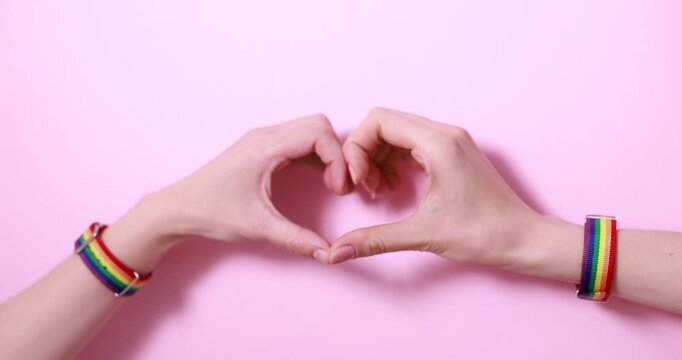 LGBT concept. Women making heart of hands on pink background, closeup