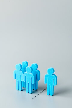 A group of blue human figures separated from a single individual figure. Exclusion, uniqueness, individuality, isolation, leadership, or social alienation concept. Copy space for text.