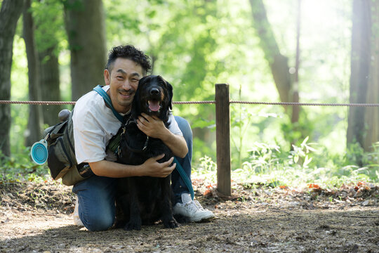 犬と公園で仲良しの飼い主の男性　大型犬かわいいカメラ目線笑顔