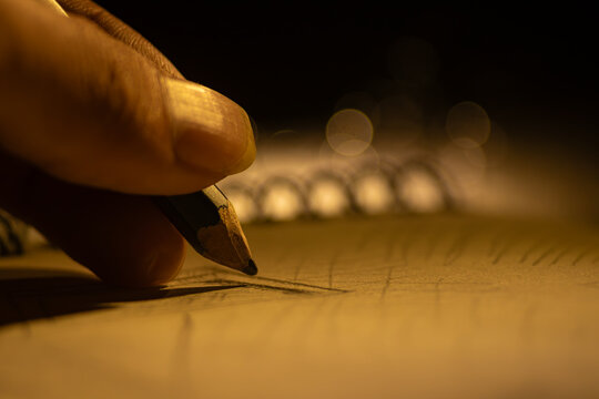 Extreme macro photograph focusing on a graphite pencil tip drawing hatching lines on a textured paper sheet