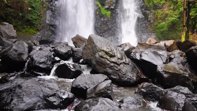 Two beautiful waterfalls Curug Cinulang West Java Indoneisa among rocks and the green scenery of trees 