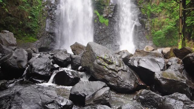 Two beautiful waterfalls Curug Cinulang West Java Indoneisa among rocks and the green scenery of trees 