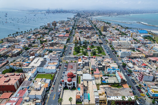 Aerial view of the coastal district of La Punta featuring historic buildings, red-domed architecture, and urban streets surrounded by the Pacific Ocean in La Punta, Callao Region, Peru.