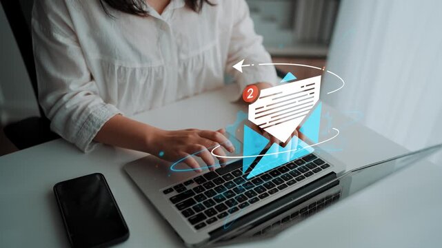 Person typing on laptop with digital envelope icon representing email notification and communication in modern workspace setting. Entropy.