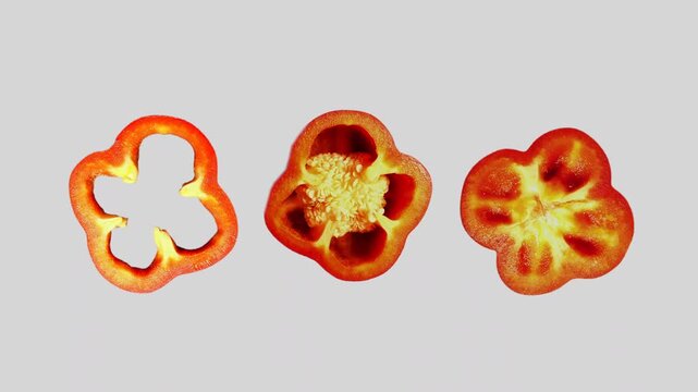 60p animated shot of three rotating red pepper slices on a white background showing different cross sections and internal structures