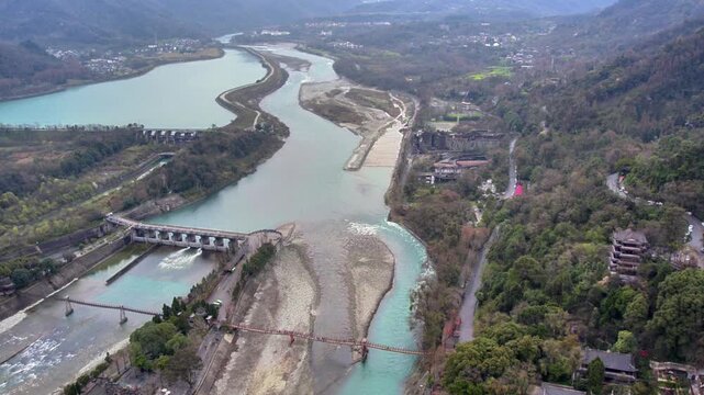 Aerial shot of an ancient water control engineering project, with split rivers, dams, and surrounding mountainous landscape with vegetation and structures.