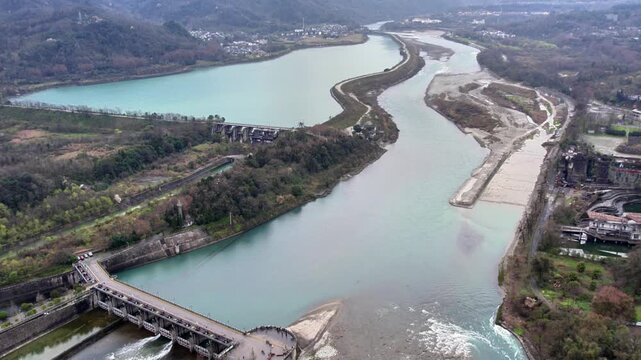 An aerial shot shows a water conservancy project diverting and regulating river flow in a mountainous area.