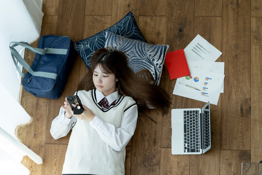 寝転んでスマホを見る日本人女子高生