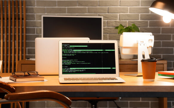 Laptop with code on screen in modern workspace