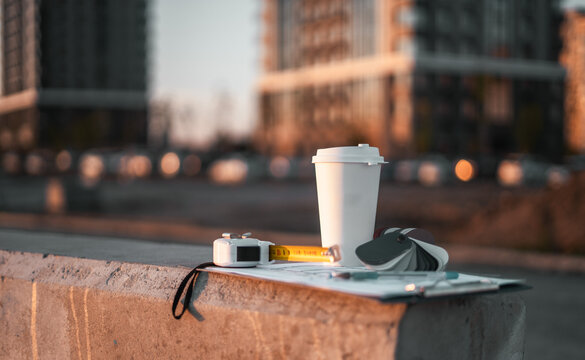 Outdoor workspace with coffee, construction documents reflects dynamic lifestyle architects and developers. Modern skyline inspires innovation, planning and future oriented thinking. Buying apartment.