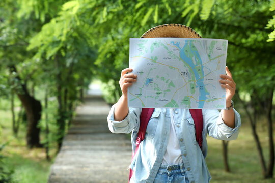 Person holding city map outdoors on green path