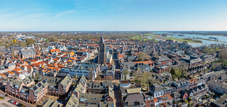 Aerial view of the historic city with its dense orange-tiled rooftops, the prominent Grote Kerk tower, and the surrounding river landscape in Gorinchem, South Holland, Netherlands.