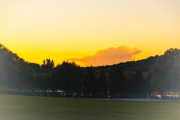Fototapeta premium Golden Sunset over Urban Park Lawn and Tree Silhouettes