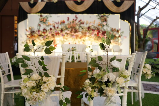 Elegant white wedding chairs decorated with flowers for a reception event