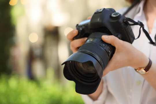 Person holding a professional DSLR camera outdoors