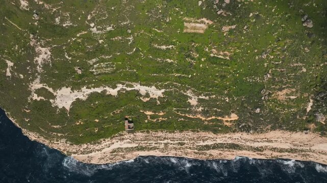 Aerial view of rugged coastal terrain meeting the ocean with lush greenery. Dingli Malta