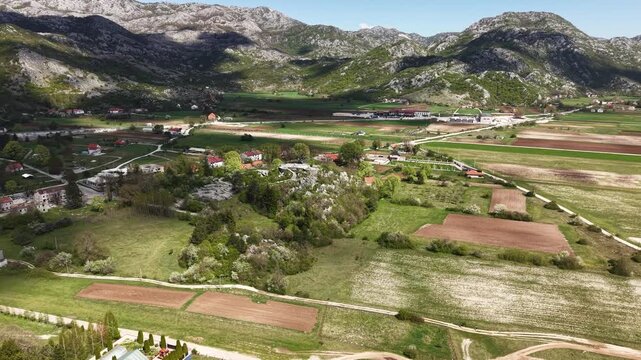 Drone Shot of Picturesque Village in Countryside of Montenegro, Clouds Shadows Above Landscape and Agricultural Fields