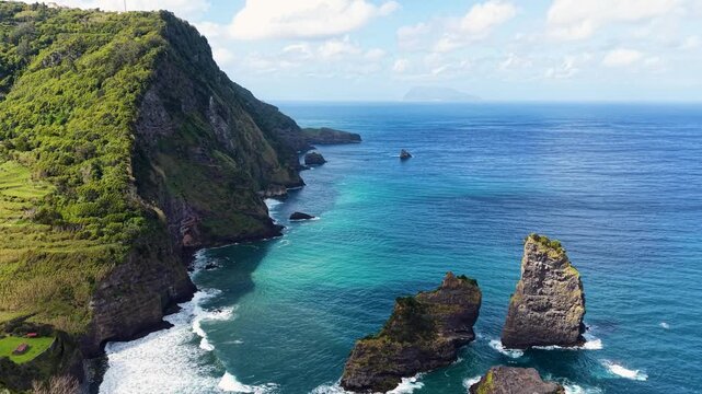 Beautiful drone footage capturing rugged volcanic cliffs turquoise Atlantic waters and striking sea stacks off the dramatic coastline of Flores Island Azores Portugal