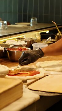 Professional Chef Spreading Tomato Sauce on Fresh Pizza Dough