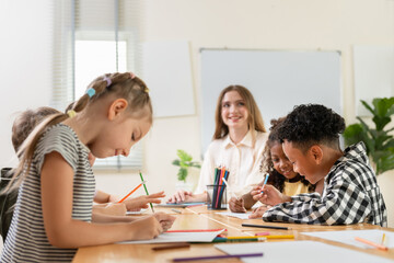 Obraz premium Education concept, Happy diverse group of primary school children doing arts and crafts in a classroom, Teacher and elementary students engaging in a creative paper craft project