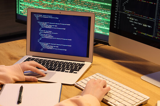 Female programmers hands working with laptop on table in office at night