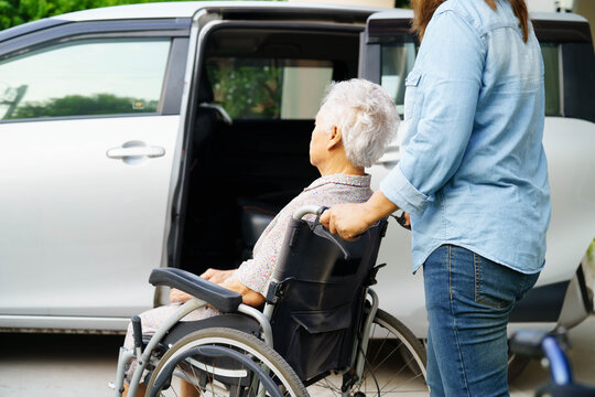 Caregiver help Asian elderly woman disability patient use wheelchair to get in car.