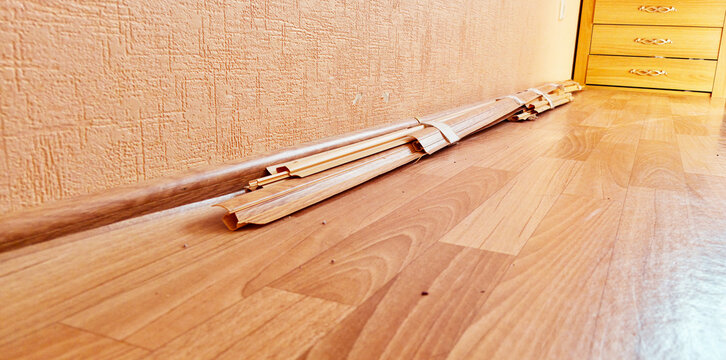A bundle of baseboards on the floor in the room; requires repair.