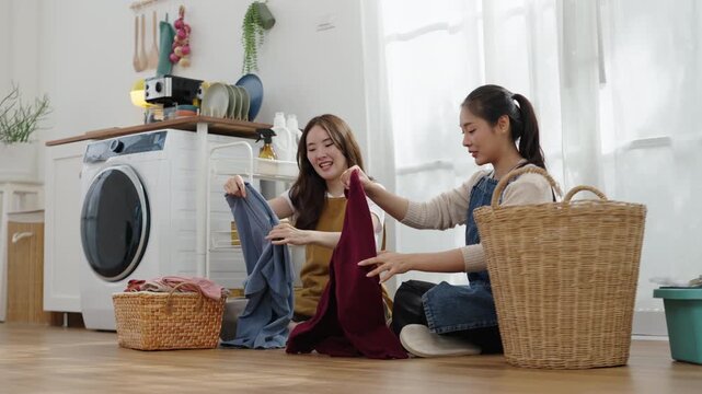Mother and daughter sort clean clothes together beside a washing machine, encouraging teamwork, responsibility, and family bonding at home.