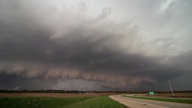 A dangerous storm approaches with a shelf cloud as cars drive on a highway in this time lapse video.
