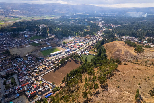 Aerial view of the town of Concepcion, featuring a stadium, residential buildings, agricultural fields, and surrounding hills in Concepcion, Junin, Peru.