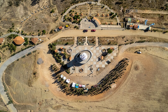 Aerial view of a central monument in a paved plaza surrounded by trees and dirt paths in Concepcion, Junin, Peru.