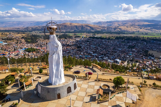 Aerial view of the Virgen de la Concepcion statue overlooking the town with a paved plaza and urban rooftops under a bright blue sky in Concepcion, Junin, Peru.