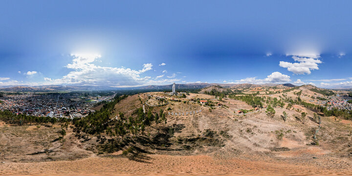 Aerial view of the statue of the Virgin of the Immaculate Conception on a hill overlooking the town of Concepcion, with dry grassy slopes and urban buildings in Concepcion, Junin, Peru.