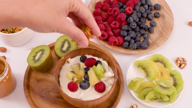 Adding Granola to a Healthy Yogurt Bowl with Fresh Fruit