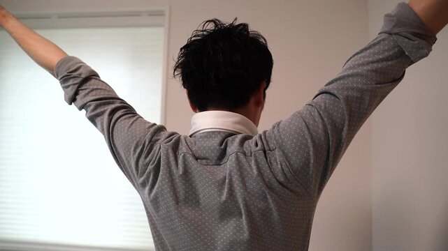 両手を上げて伸びをする男性