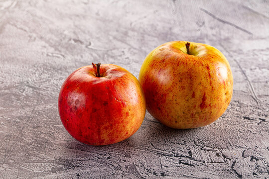 Two ripe apples on textured gray surface