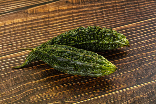 Two green bitter melons on rustic wooden surface
