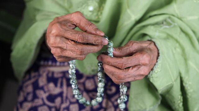 senior woman using beads counting prayers in Islam.