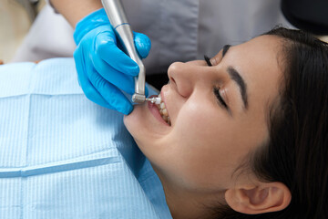 Fototapeta premium Young woman getting her teeth polished in dental clinic. Professional dental cleaning concept