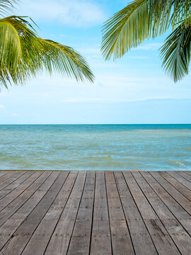 Tropical ocean view with wooden deck and palm leaves framing blue sea horizon, featuring exotic travel destination, summer vacation background, coastal relaxation, resort lifestyle, and copy space.