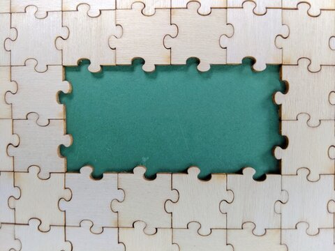 jigsaw puzzle background. Wooden jigsaw puzzle with central missing piece reveals green background, symbolizing incompleteness, problem-solving and unfinished tasks.