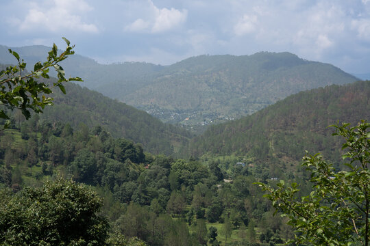 Lush green Himalayan mountain valley with scattered village houses in Uttarakhand