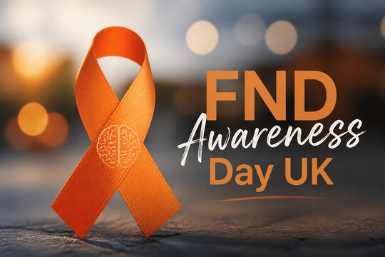 An orange awareness ribbon rests on a surface with blurred lights in the background for FND Awareness Day UK.