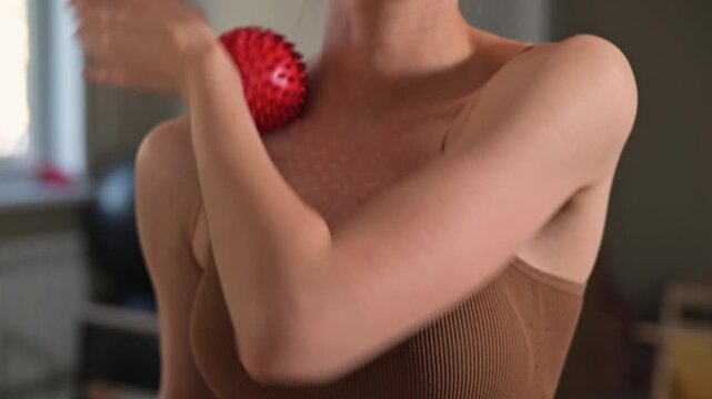 A person performs upper body exercises with a massage ball in a room designed for physical activity