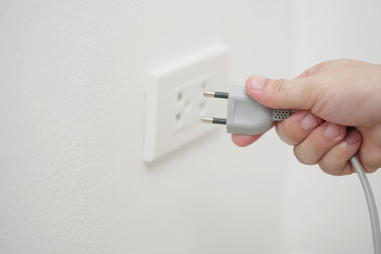 close up hand plugging adapter Electrical appliances with outlet socket plug  ,electric safety concept