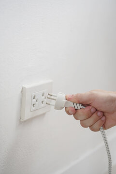 close up hand plugging adapter Electrical appliances with outlet socket plug  ,electric safety concept