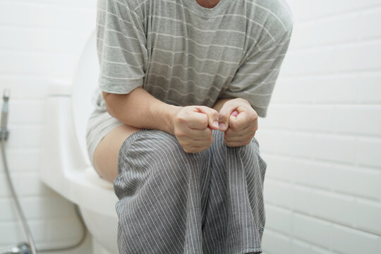 portrait of a man suffers from diarrhea his stomach painful. ache and problem. of toilet bowl. constipation in bathroom. Hygiene, health care concept.
