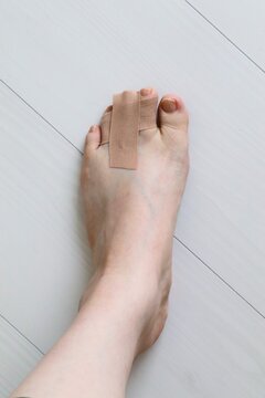 打撲した足指をテーピングで固定する応急処置。セルフケアや怪我の回復、医療をイメージした写真素材。