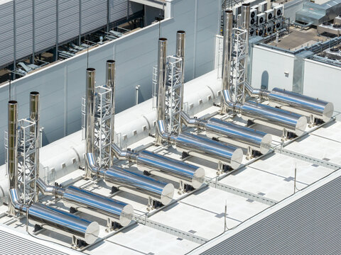 Aerial view of the industrial exhaust system with shiny metal chimneys on the rooftop of an advanced AI datacenter in Warsaw, Masovian Voivodeship, Poland.