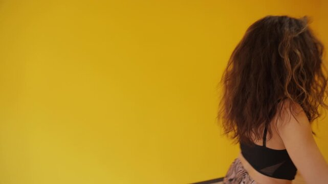 Expressive woman dancing alone in yellow room